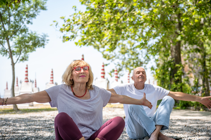 Older woman and man doing yoga outside